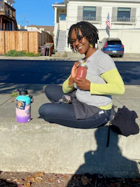 a woman sitting on a curb with a cup of coffee